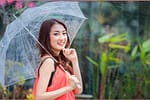 young Thai lady standing with under umbrella under rainning