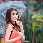young Thai lady standing with under umbrella under rainning