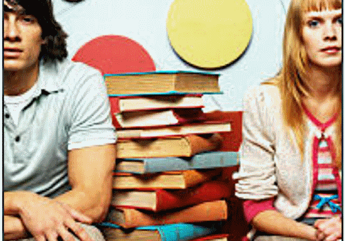 Two students sitting between books